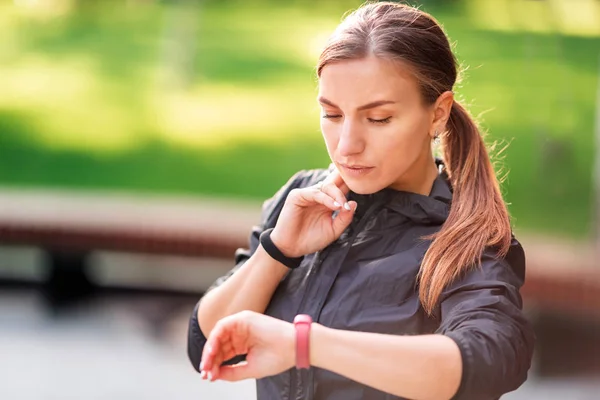 Bella ragazza sportiva controllando il polso durante gli esercizi di fitness, jogging — Foto Stock