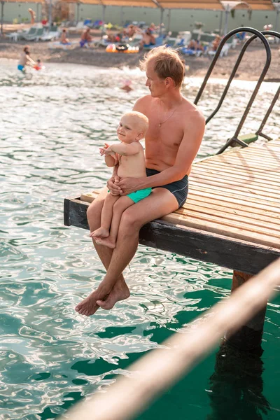 Baba ve oğul ahşap iskeleden bacaklarını sallıyor — Stok fotoğraf