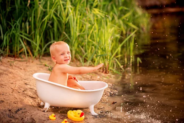 可爱的男婴在河岸的浴缸里玩耍 — 图库照片