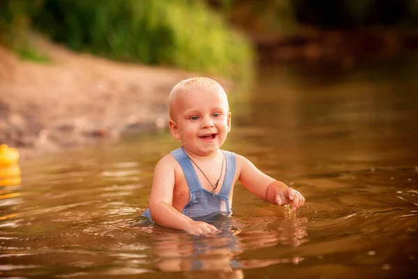 Schattige baby jongen spelen op de oever van de rivier — Stockfoto