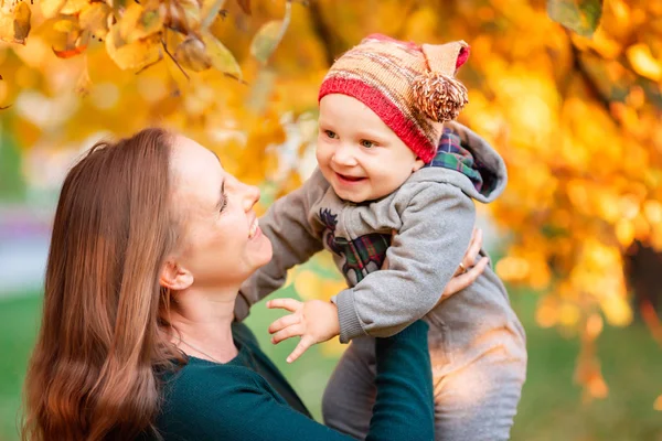 Happy mother and baby in autumn leaves — Stock Photo, Image