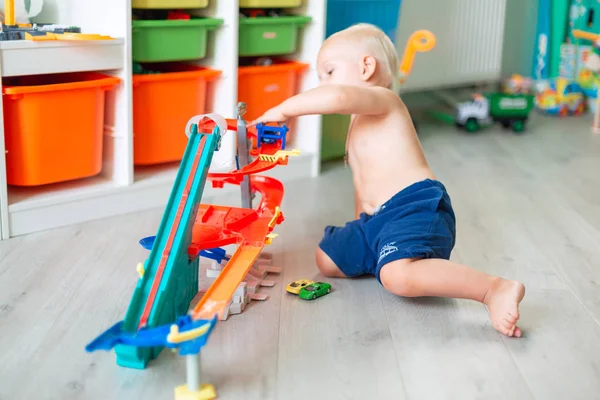 Lindo bebé niño jugando con coches de juguete en pista — Foto de Stock