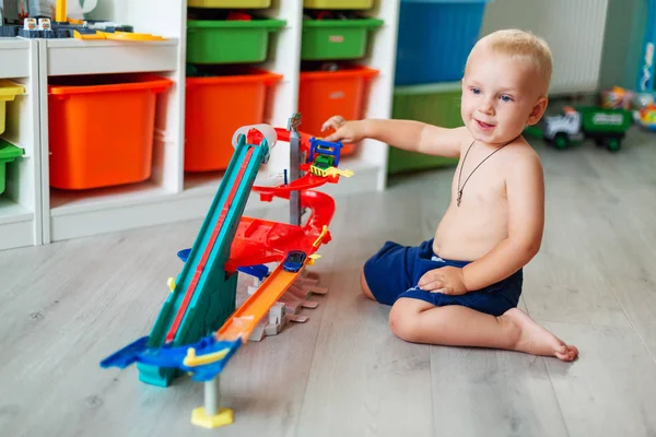 Bonito menino brincando com carros de brinquedo na pista — Fotografia de Stock