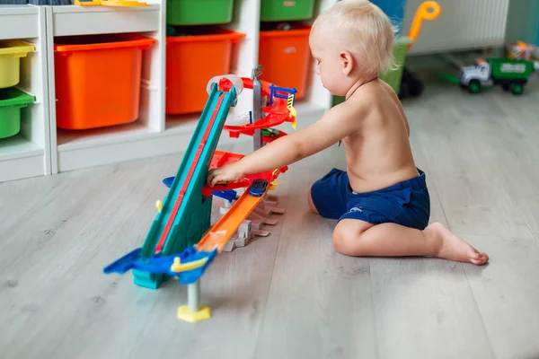Niedlicher kleiner Junge spielt mit Spielzeugautos auf der Strecke — Stockfoto