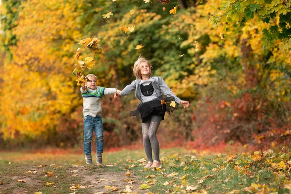 Niños felices con hojas de otoño en el parque —  Fotos de Stock