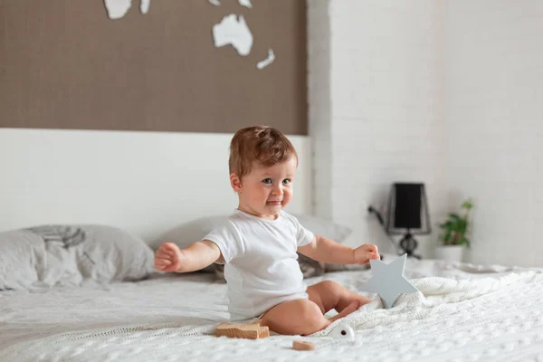 Glückliches Baby sitzt auf einem großen Bett — Stockfoto