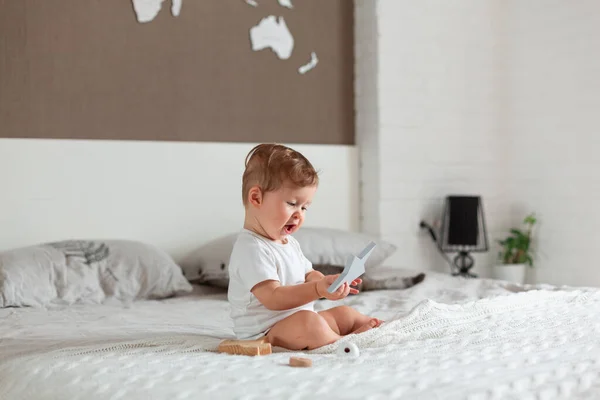 Glückliches Baby sitzt auf einem großen Bett — Stockfoto