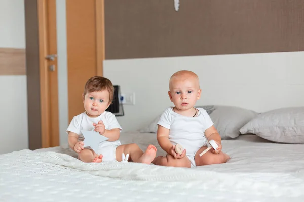 Dois bebês felizes sentados em uma cama — Fotografia de Stock
