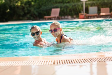 Mutlu güzel kızlar tatil köyündeki havuzda eğleniyor.