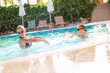 Mutlu güzel kızlar tatil köyündeki havuzda eğleniyor.