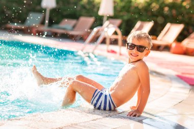 Mutlu küçük çocuk tatil havuzunda eğlenmek