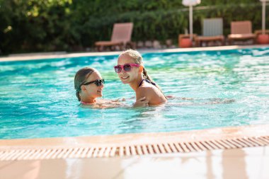 Mutlu güzel kızlar tatil köyündeki havuzda eğleniyor.