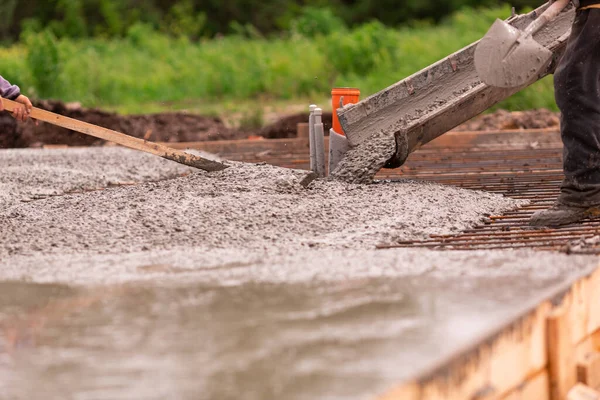 Lay of the cement or concrete into the foundation formwork from concrete mixer. Building house foundation