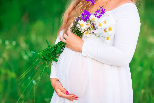 美しい晴れた日に自然の中でリラックスした美しい若い妊婦 背景のフィールドと自然の中で妊娠中の腹の閉鎖 — ストック写真