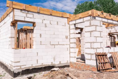İnşaat halindeki bir evin inşaatı: gaz, beton bloklardan duvarlar, pencerelerin ahşap takviyesi ve beton temeller.