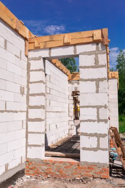 İnşaat halindeki bir evin inşaatı: gaz, beton bloklardan duvarlar, pencerelerin ahşap takviyesi ve beton temeller.