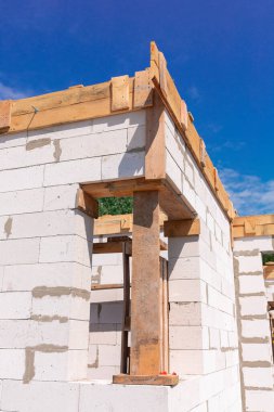 İnşaat halindeki bir evin inşaatı: gaz, beton bloklardan duvarlar, pencerelerin ahşap takviyesi ve beton temeller.