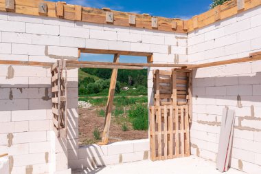 İnşaat halindeki bir evin inşaatı: gaz, beton bloklardan duvarlar, pencerelerin ahşap takviyesi ve beton temeller.