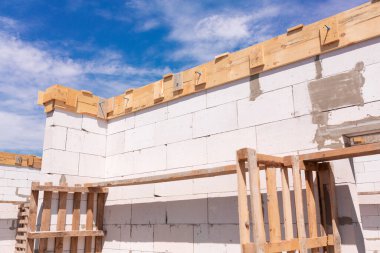 İnşaat halindeki bir evin inşaatı: gaz, beton bloklardan duvarlar, pencerelerin ahşap takviyesi ve beton temeller.
