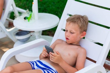 Çocuk telefonda oyun oynuyor. Deniz kıyısındaki tatilde çocuklar için Gadget bağımlılığı sorunu