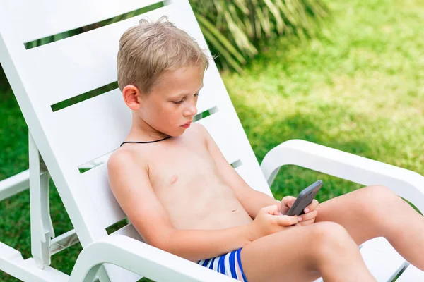 少年は電話でゲームをしている 海辺の概念で休暇中の子供のためのガジェット依存障害の問題 — ストック写真