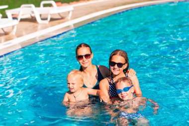 Mutlu çocuklar havuzda eğleniyor. Çocuklar yaz tatili boyunca açık deniz tatil beldesinde oynuyorlar. Tatildeki çocuklar için su ve su serpme eğlencesi.