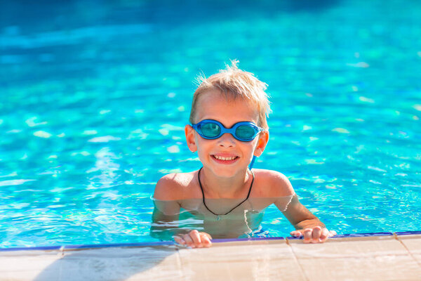 Симпатичный счастливый мальчик в плавании и нырянии в бассейне