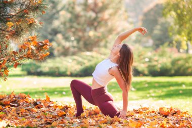 Parkta yoga yapan güzel bir genç kadın.