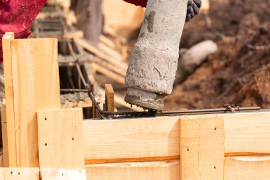 Otomatik pompayla temel çalışmalarına çimento ya da beton döşeyen inşaat işçilerini kapatın. Ev temelleri oluşturuluyor