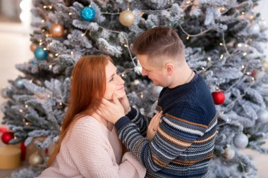 Mutlu çift evde Noel ağacının yanında eğleniyor.