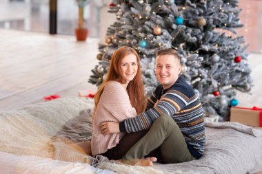 Mutlu çift evde Noel ağacının yanında eğleniyor.