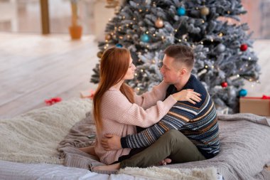 Mutlu çift evde Noel ağacının yanında eğleniyor.