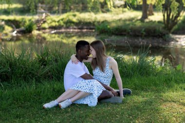 Genç bir çift, açık havada yaz gününün tadını çıkarıyor. Siyah bir adam ve beyaz bir kadın, doğal bir bahçe bahçesinde birlikte. Romantizm, sevgi ve çeşitliliği barışçıl, güneşli bir ortamda ifade ediyorlar.