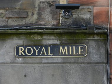 Royal Mile sokak tabelası, şehirdeki tipik simge, nemli duvarda altın harflerle siyah dikdörtgen plaka.
