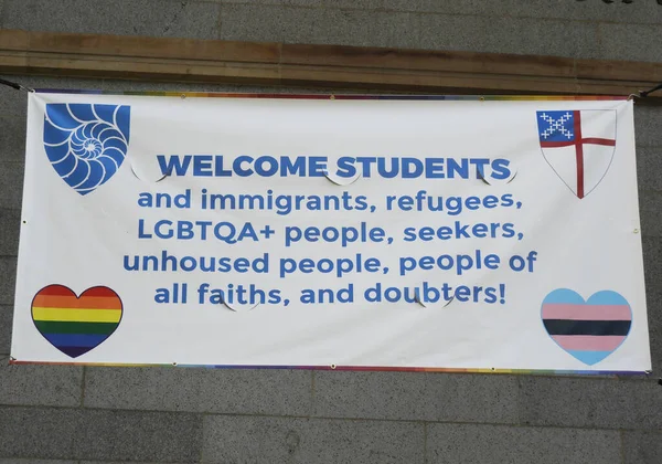 Banner öğrencileri, göçmenleri, lgbtqa + 'yı, yerleşmeyen, mavi harfli beyaz bez ve lgtb' yi ve transseksüel bayrakları karşılıyor.