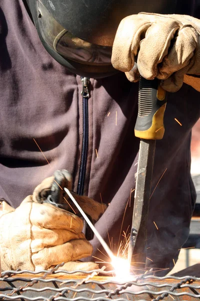 Standart koruma ekipmanı takan bir metal parçasını kaynaklıyor.