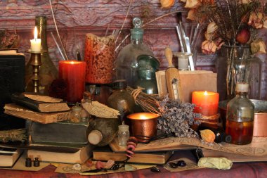 Kara büyü büyü. Wiccan büyüler ve otlar. Hala canlı: Eski yağ lambaları, antika kitap, bakır kase, ilaç şişeleri, lavanta, Pulsatilla pratensis bir antika arka plan üzerinde yanan bir muma gül tomurcukları kurutulmuş. Wicca arka plan.