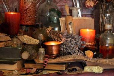 Kara büyü büyü. Wiccan büyüler ve otlar. Hala canlı: Eski yağ lambaları, antika kitap, bakır kase, ilaç şişeleri, lavanta, Pulsatilla pratensis bir antika arka plan üzerinde yanan bir muma gül tomurcukları kurutulmuş. Wicca arka plan.