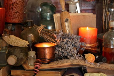 Kara büyü büyü. Wiccan büyüler ve otlar. Hala canlı: Eski yağ lambaları, antika kitap, bakır kase, ilaç şişeleri, lavanta, Pulsatilla pratensis bir antika arka plan üzerinde yanan bir muma gül tomurcukları kurutulmuş. Wicca arka plan.