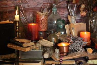 Kara büyü büyü. Wiccan büyüler ve otlar. Hala canlı: Eski yağ lambaları, antika kitap, bakır kase, ilaç şişeleri, lavanta, Pulsatilla pratensis bir antika arka plan üzerinde yanan bir muma gül tomurcukları kurutulmuş. Wicca arka plan.