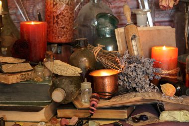 Kara büyü büyü. Wiccan büyüler ve otlar. Hala canlı: Eski yağ lambaları, antika kitap, bakır kase, ilaç şişeleri, lavanta, Pulsatilla pratensis bir antika arka plan üzerinde yanan bir muma gül tomurcukları kurutulmuş. Wicca arka plan.