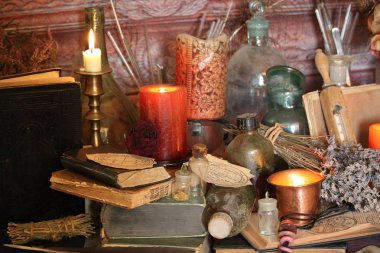Kara büyü büyü. Wiccan büyüler ve otlar. Hala canlı: Eski yağ lambaları, antika kitap, bakır kase, ilaç şişeleri, lavanta, Pulsatilla pratensis bir antika arka plan üzerinde yanan bir muma gül tomurcukları kurutulmuş. Wicca arka plan.