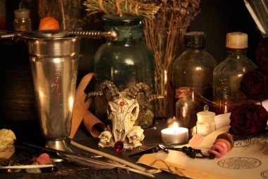 Kara büyü büyü. Wiccan büyüler ve otlar. Hala canlı: Eski yağ lambaları, antika kitap, bakır kase, ilaç şişeleri, lavanta, Pulsatilla pratensis bir antika arka plan üzerinde yanan bir muma gül tomurcukları kurutulmuş. Wicca arka plan.