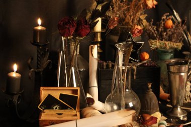 Kara büyü büyü. Wiccan büyüler ve otlar. Hala canlı: Eski yağ lambaları, antika kitap, bakır kase, ilaç şişeleri, lavanta, Pulsatilla pratensis bir antika arka plan üzerinde yanan bir muma gül tomurcukları kurutulmuş. Wicca arka plan.