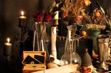 Kara büyü büyü. Wiccan büyüler ve otlar. Hala canlı: Eski yağ lambaları, antika kitap, bakır kase, ilaç şişeleri, lavanta, Pulsatilla pratensis bir antika arka plan üzerinde yanan bir muma gül tomurcukları kurutulmuş. Wicca arka plan.
