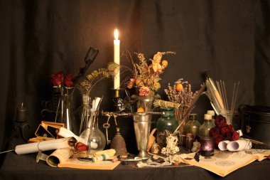 Kara büyü büyü. Wiccan büyüler ve otlar. Hala canlı: Eski yağ lambaları, antika kitap, bakır kase, ilaç şişeleri, lavanta, Pulsatilla pratensis bir antika arka plan üzerinde yanan bir muma gül tomurcukları kurutulmuş. Wicca arka plan.