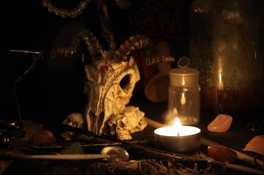 Kara büyü büyü. Wiccan büyüler ve otlar. Hala canlı: Eski yağ lambaları, antika kitap, bakır kase, ilaç şişeleri, lavanta, Pulsatilla pratensis bir antika arka plan üzerinde yanan bir muma gül tomurcukları kurutulmuş. Wicca arka plan.