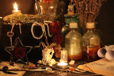 Kara büyü büyü. Wiccan büyüler ve otlar. Hala canlı: Eski yağ lambaları, antika kitap, bakır kase, ilaç şişeleri, lavanta, Pulsatilla pratensis bir antika arka plan üzerinde yanan bir muma gül tomurcukları kurutulmuş. Wicca arka plan.