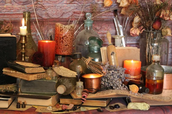 Black Magic Spells. Wiccan spells and herbs. Still Live: Old oil lamps, antique books, dried rose buds, a burning candle in a copper bowl, medicine bottles, lavender, Pulsatilla pratensis on an antique background. Wicca background.