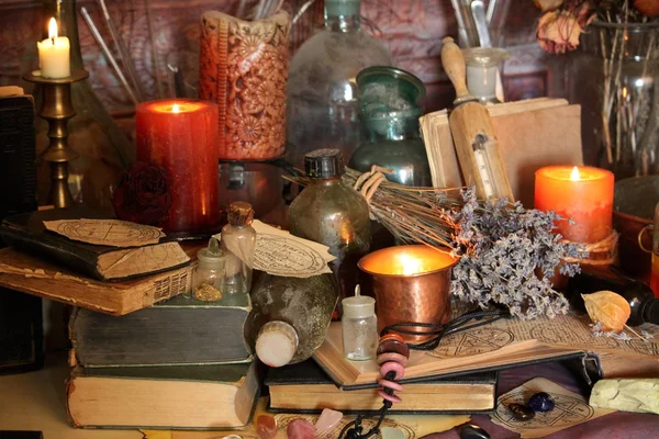 Kara büyü büyü. Wiccan büyüler ve otlar. Hala canlı: Eski yağ lambaları, antika kitap, bakır kase, ilaç şişeleri, lavanta, Pulsatilla pratensis bir antika arka plan üzerinde yanan bir muma gül tomurcukları kurutulmuş. Wicca arka plan.
